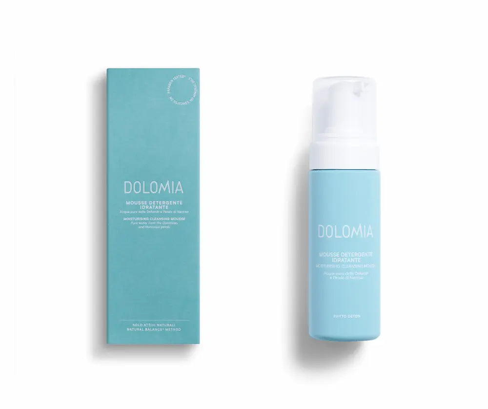 Dolomia Mousse Detergente Idratante, hellblaue Pumpflasche mit weißem Spender neben türkisfarbener Faltschachtel, Vorderansicht