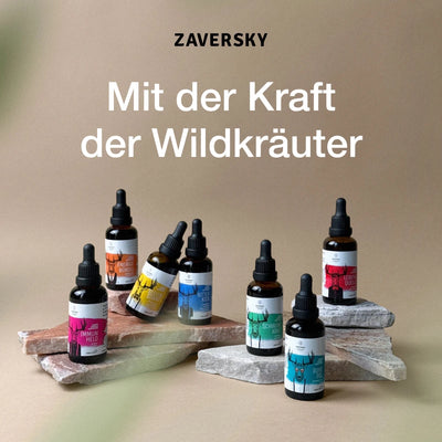 Sieben Zaversky Wildkräuter-Tropfenflaschen aus Braunglas mit bunten Etiketten auf Steinplatten, Schriftzug „Mit der Kraft der Wildkräuter“